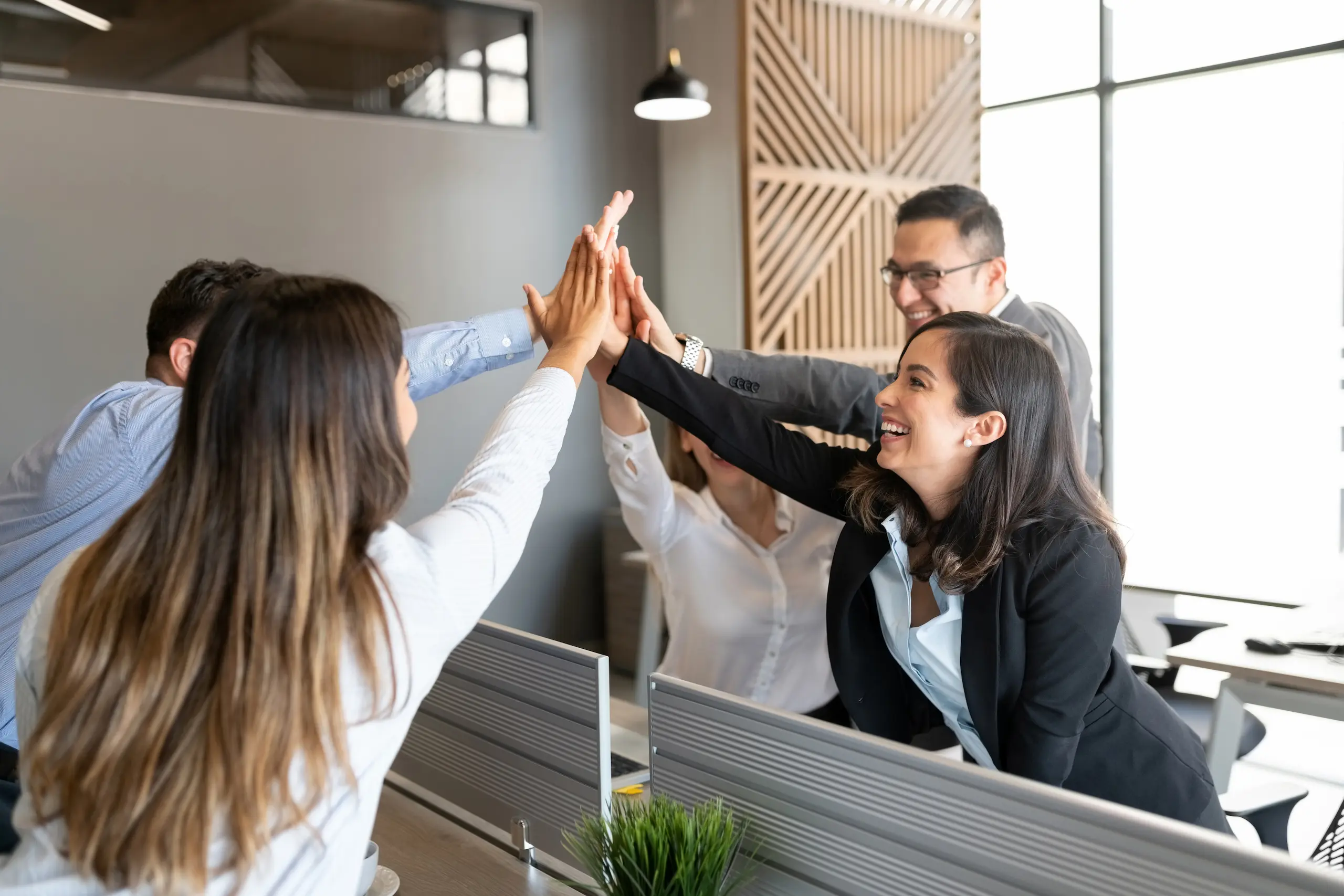 Equipo de trabajo celebrando un logro profesional en la oficina, representando el éxito en la gestión de programas de capacitación y cumplimiento de procesos laborales en la empresa.