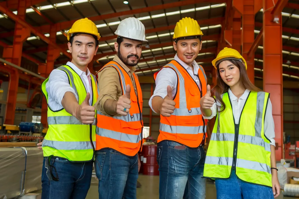 Grupo de trabajadores y supervisores con chalecos y cascos.
