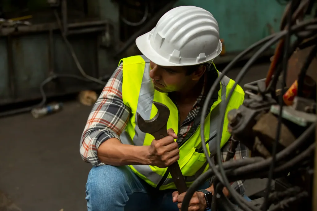 mecanico-trabajando-con-seguridad-industrial-y-medio-ambiente Mecánico con llave y uniforme de protección industrial.